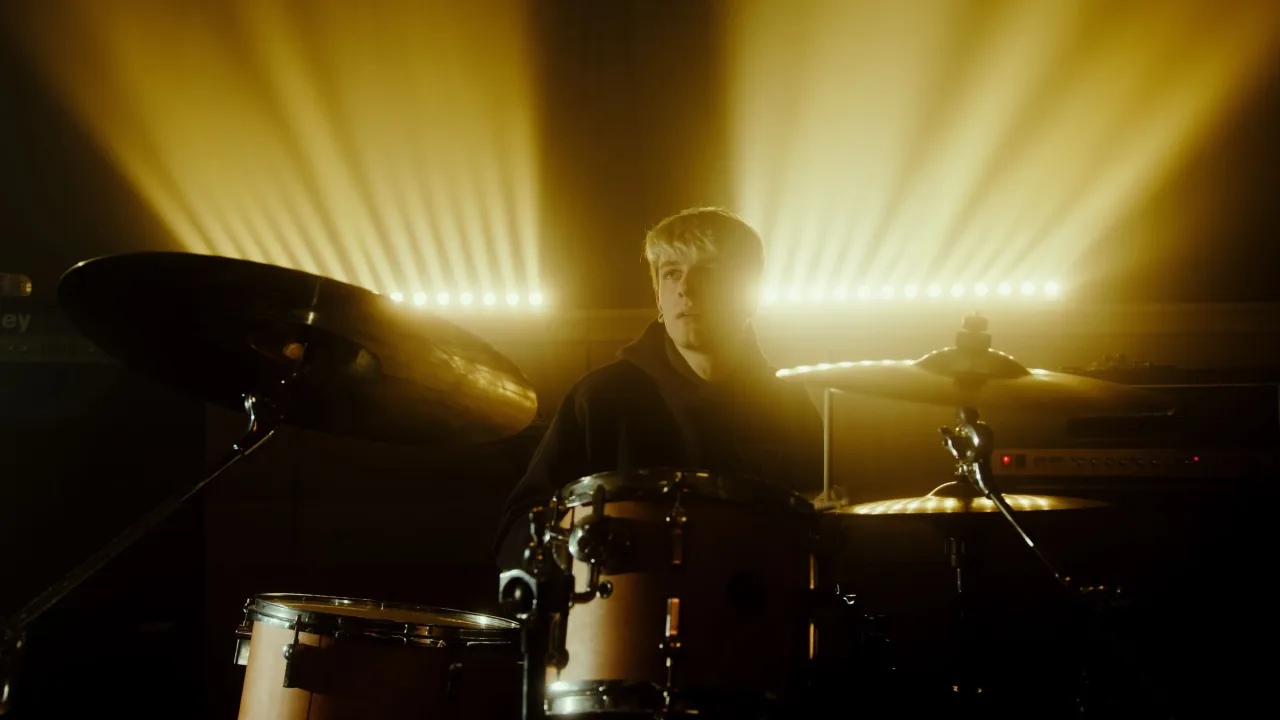 Baterista tocando ritmos de festa junina na bateria em um arraiá de São João com bandeirinhas e luz âmbar